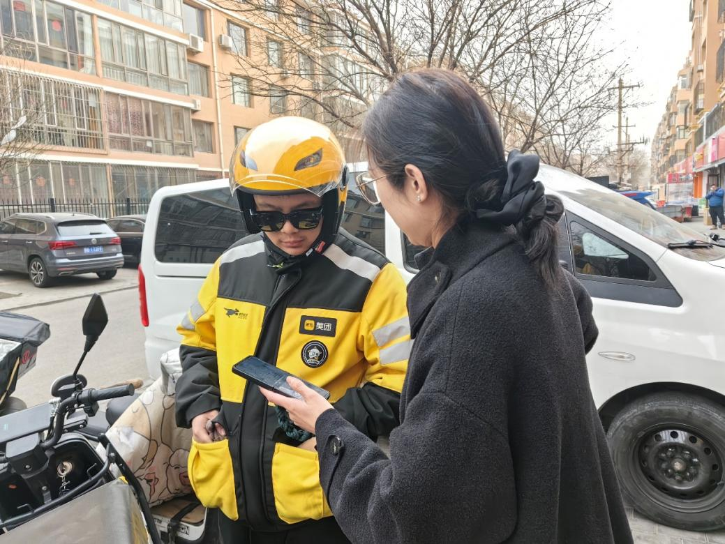 社区工作人员在外卖站点了解骑手需求并邀请骑手加入社区志愿服务群。青山区万青路街道办事处供图